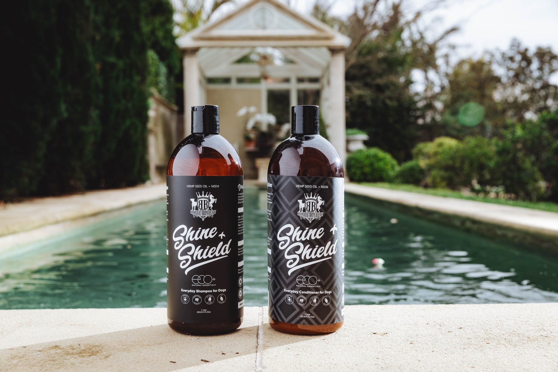 Rogue Royalty Shine & Shield natural dog shampoo and conditioner beside a swimming pool