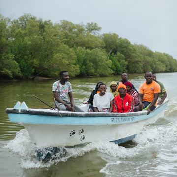 Group of people on a boat in a body of water with trees in the background