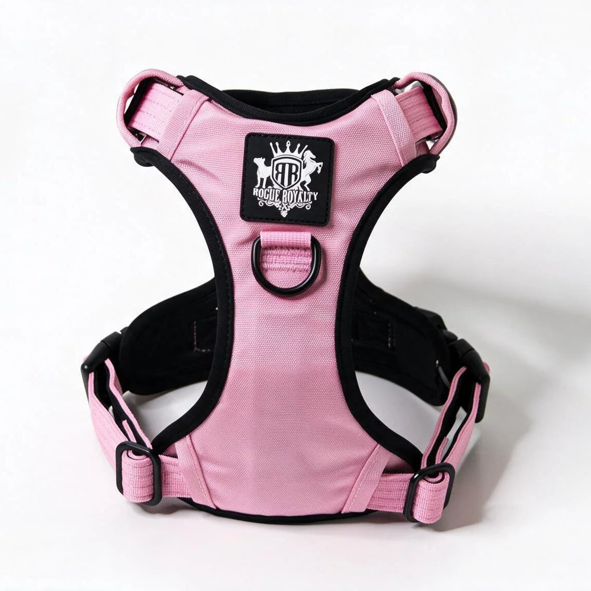 Pink and black dog harness with a central logo patch, photographed on a clean white background.