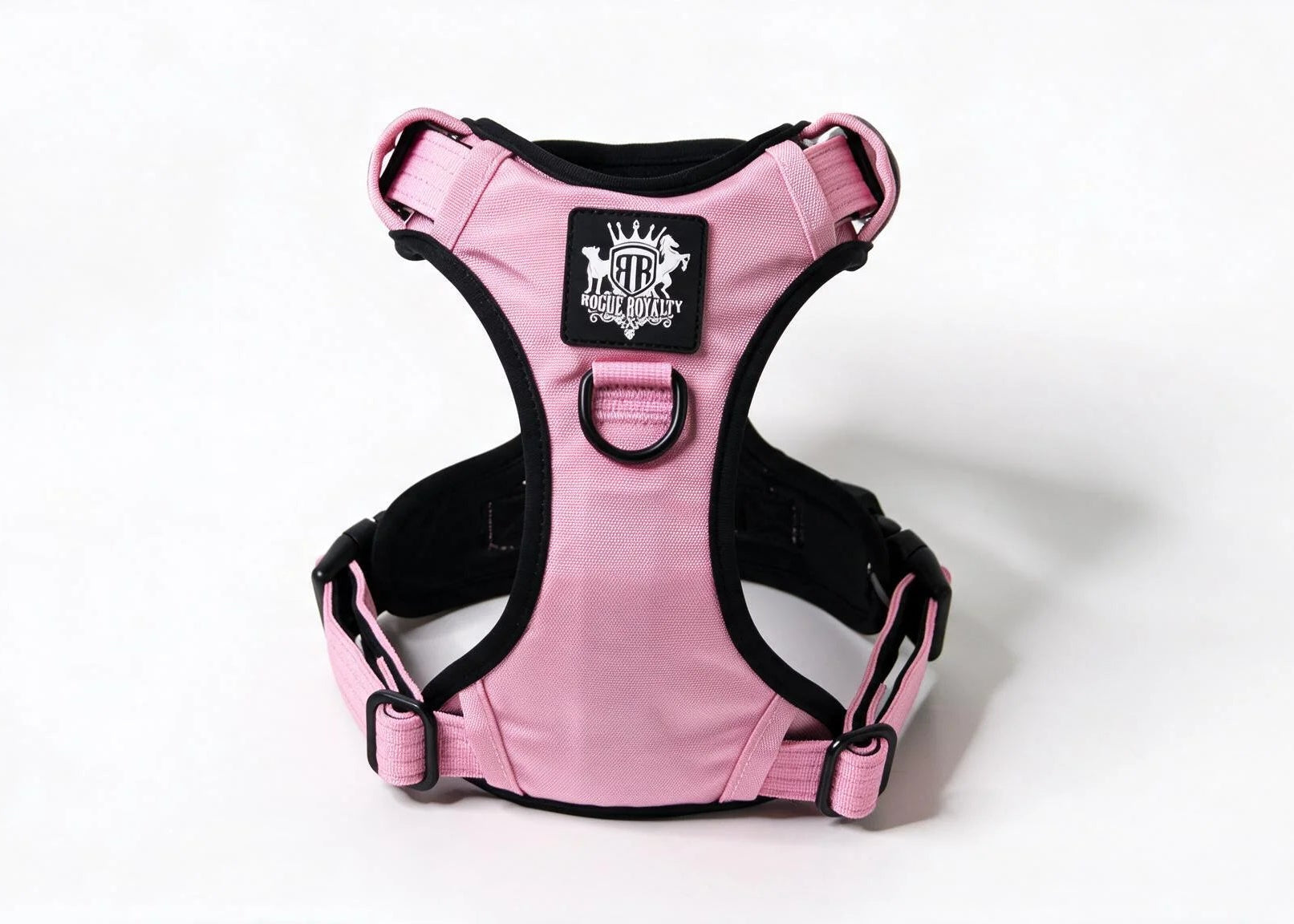 Pink and black dog harness with a central logo patch, photographed on a clean white background.